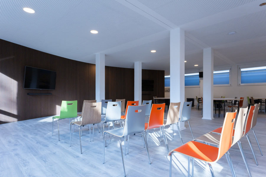 Meetup-Projektraum mit gro&szlig;en Bildschirmen an abgerundeten W&auml;nden mit braunen Paneelen