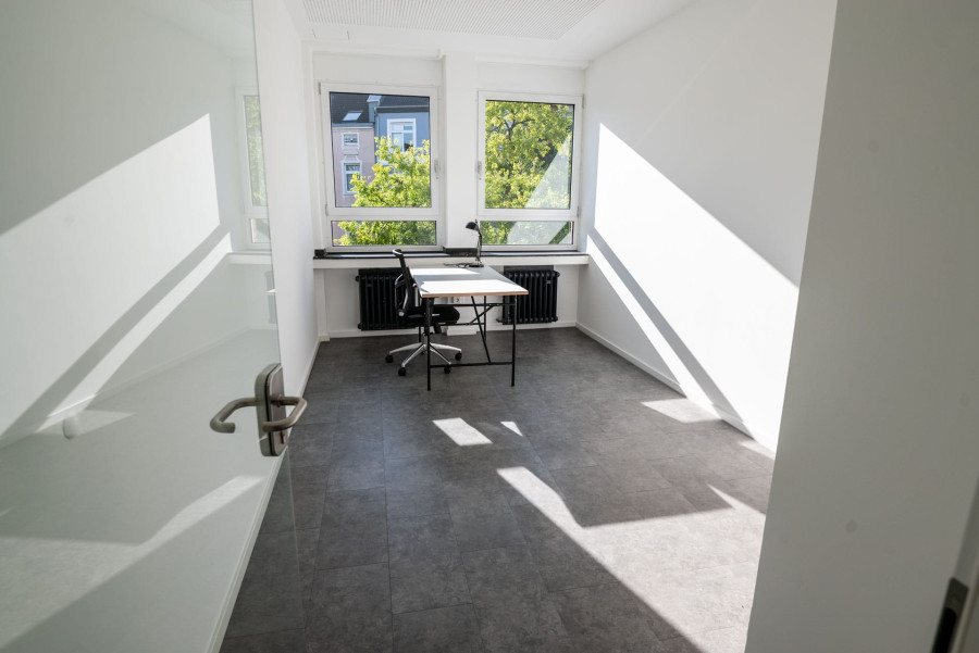 Kleines B&uuml;ro mit einem Schreibtisch-Setup und einer offenen Glas&uuml;r