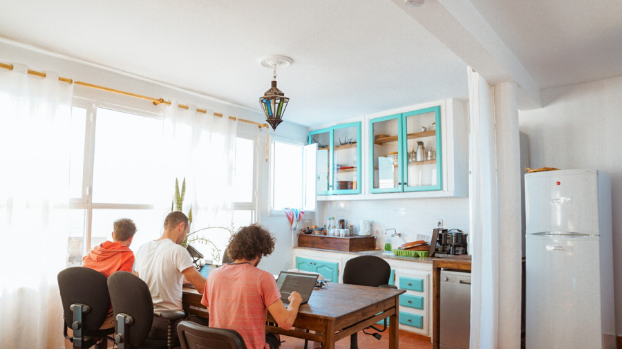 Personen sitzen gemeinsam an einem K&uuml;chentisch und arbeiten