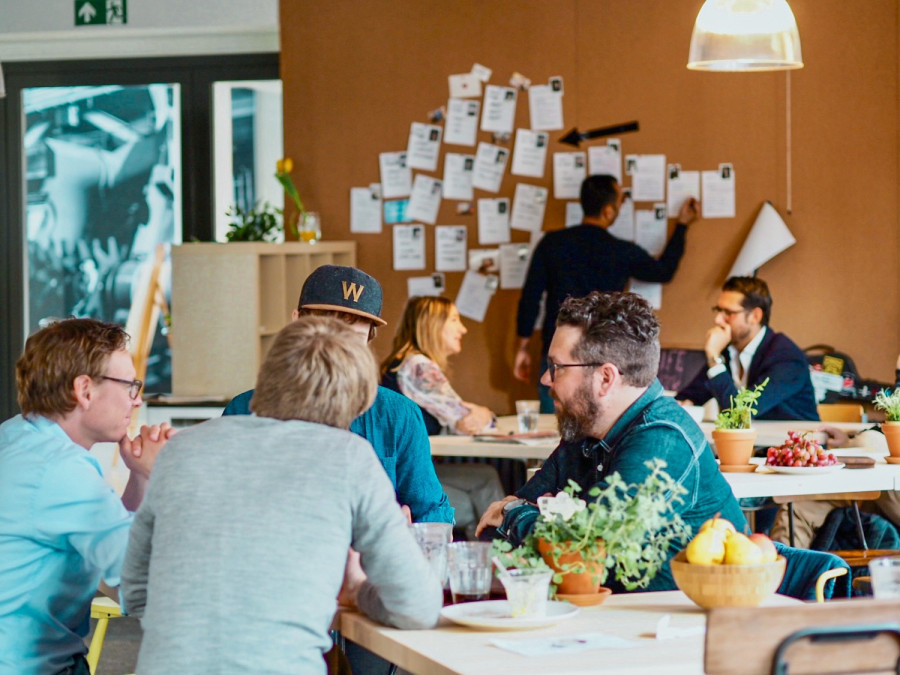 Foto des Coworking Spaces, wo Menschen sitzen und sich unterhalten
