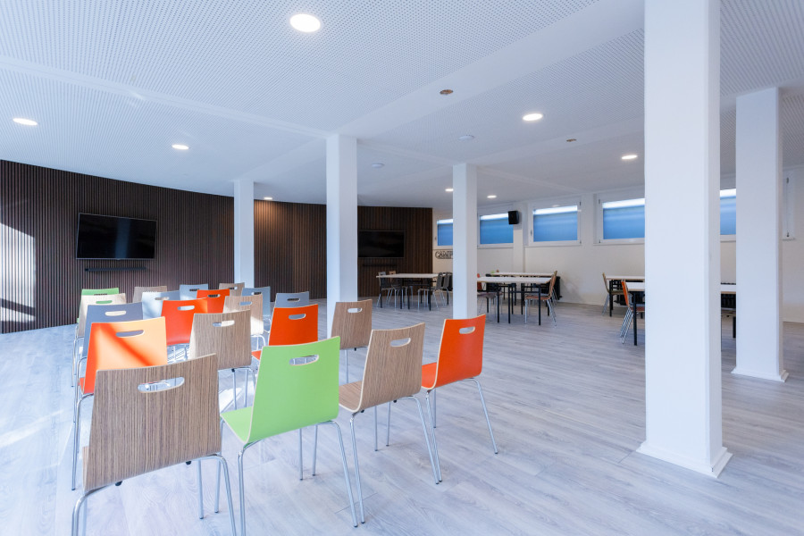 Meetup-Projektraum mit gro&szlig;en Bildschirmen an abgerundeten W&auml;nden mit braunen Paneelen