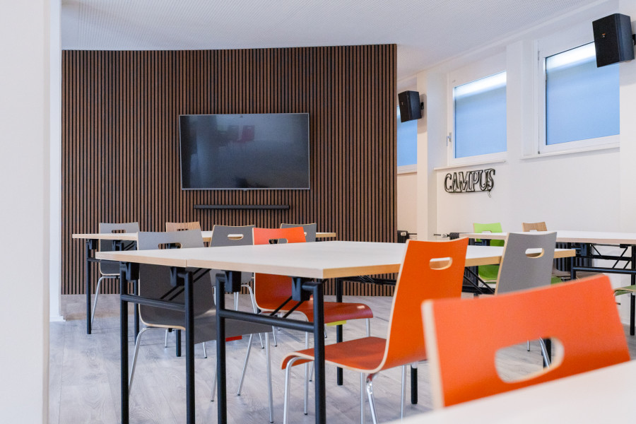 Meetup-Projektraum mit gro&szlig;en Bildschirmen an abgerundeten W&auml;nden mit braunen Paneelen