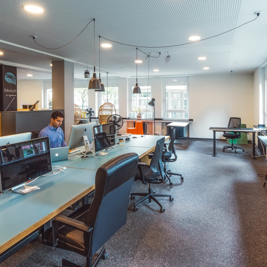 Coworking Bereich mit einer langen Tafel, an der Personen sitzen und arbeiten