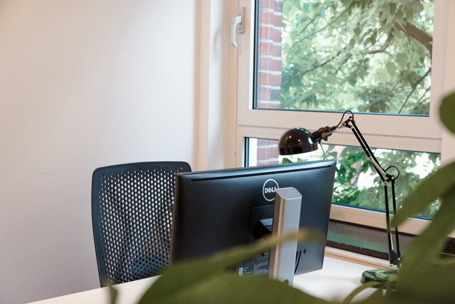 Close Up eines Schreibtisches mit Bildschirm und Lampe